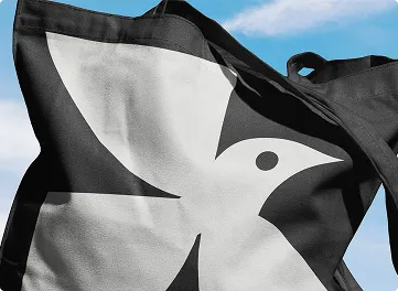 Loti tote bag with bird logo against the sky